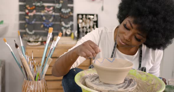 Young Black Woman Painting a Clay Bowl at Workshop