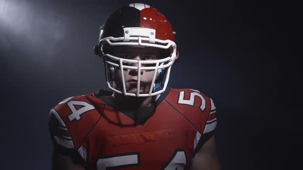 Portrait of Determined Professional American Football Player in Helmet in Dramatic Light Throwing Up