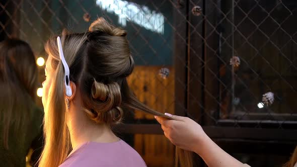 Hairdresser Doing Hairstyle to Young Blonde Woman Applying Hairspray in Beauty Salon