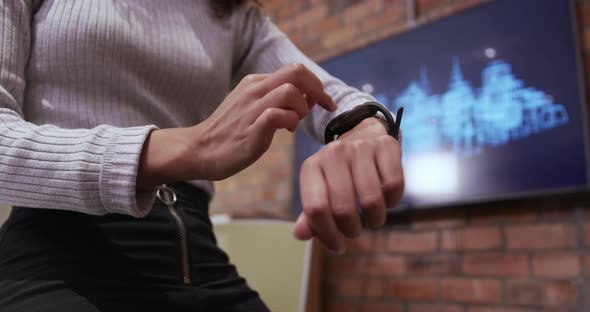 Mid section of creative businesswoman using smartwatch