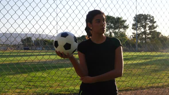 A strong and confident female athlete soccer player holding a football during a competitive womens s