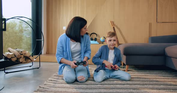 Mother and Her Small Son which Sitting on the Floor and Enjoying Video Games