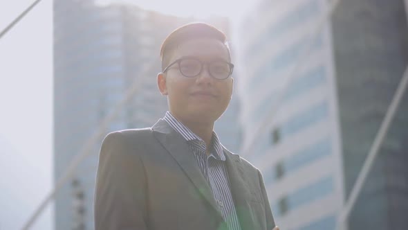 Portrait handsome Asian businessman smiling and looking at camera standing on the urban city.