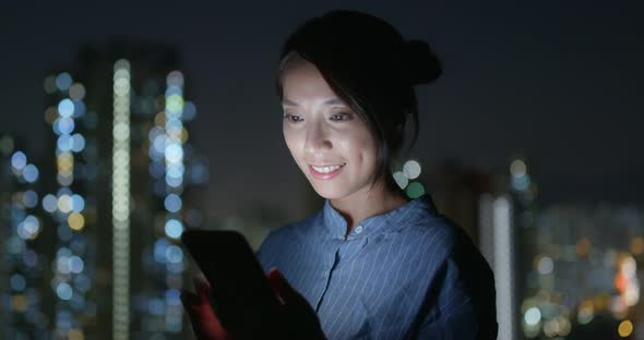Woman look at cellphone with the building background at night