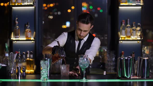 Barman Pouring Cocktail To Glass in Bar