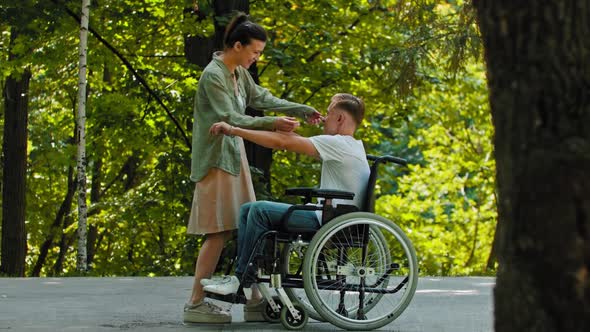 Disabled Man in a Wheelchair Rides to His Female Friend and Hugging Her