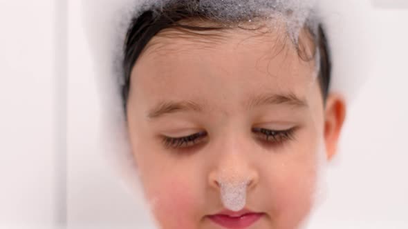 Three Year Old Child with Big Brown Eyes Is Sitting in a White Bathroom