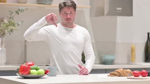 Middle Aged Man Showing Thumbs Down While Standing in Kitchen