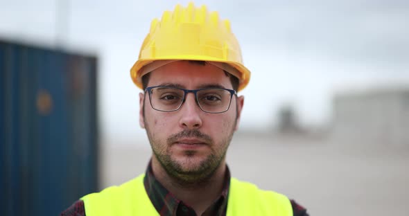 Young man looking on camera working at freight terminal port on background