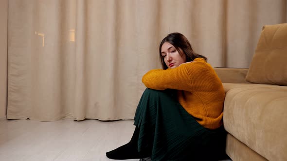 Depressed Lady in Sweater and Skirt Sits on Wooden Floor