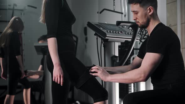 A Man Dresses a Woman in Electric Stimulation Fitness Suit