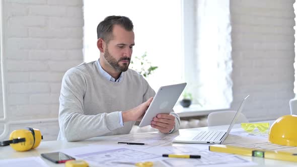 Young Architect with Laptop Using Tablet in Office