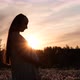 A Young Pregnant Woman Sits in a Flower Field at Sunset - VideoHive Item for Sale