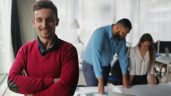 Handsome Smiling Young Man with Crossed Arms Looking at Camera