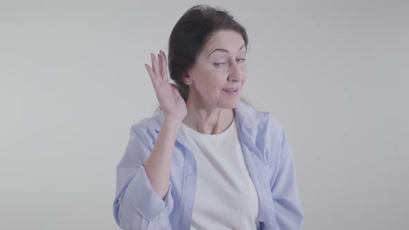 Portrait of Brunette Woman Putting Hand To Ear and Looking at Camera with Interest. Positive