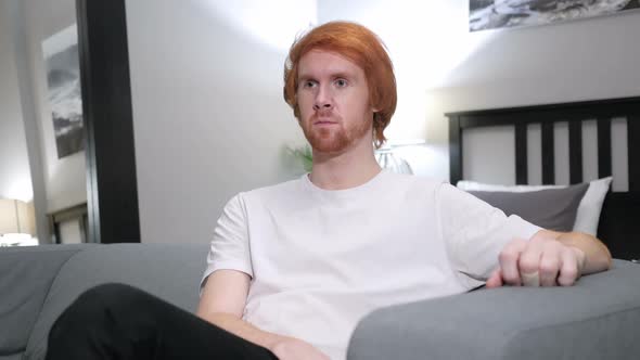 Redhead Man Sitting on Couch in Bedroom