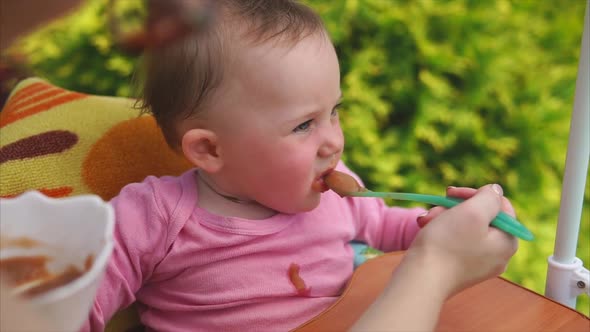 Baby Girl Eating Vegetable Puree Mother Feeding Her with Spoon