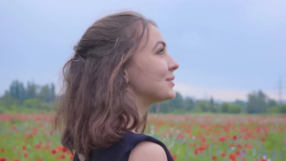 Side View of a Pretty Girl in the Poppy Field Looking Away with a Happy Wide Smile. Connection with