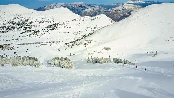 Aerial view of mountains surrounded by snow and pine trees in Kalavryta Ski.