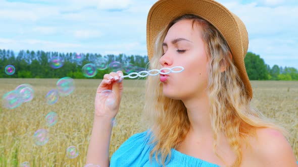 A Woman Blows Soap Bubbles Next To a Cereal Field