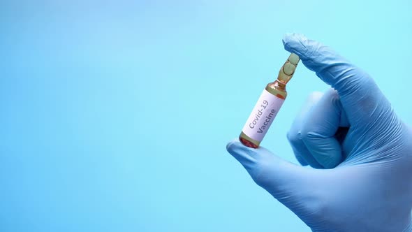 Hand in Latex Gloves Holding Glass Ampoule Vaccine with Copy Space