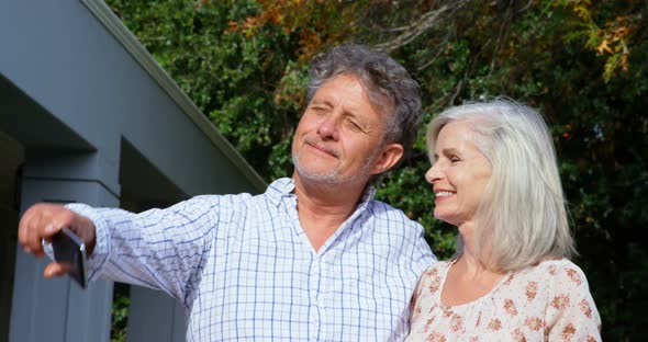 Senior couple taking selfie in homeyard 4k