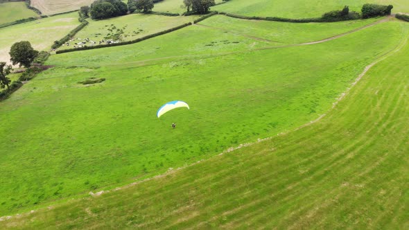 Aerial shot of a Paraglider taking off a hill with the English countryside behind