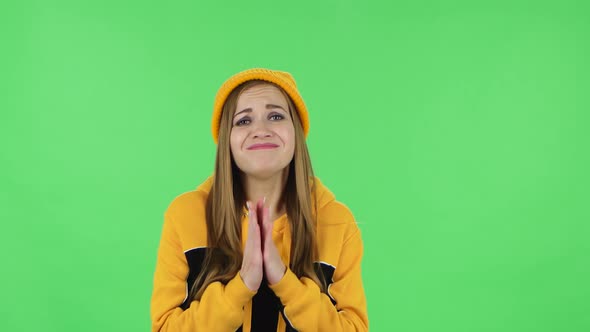 Portrait of Modern Girl in Yellow Hat Is Keeping Palm Together and Asking for Something