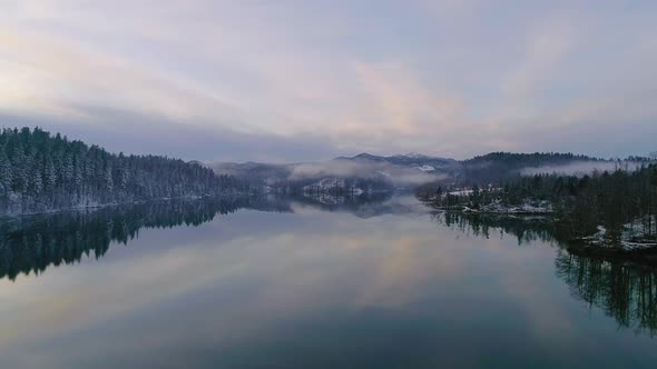 Aerial view of winter lake with reflection and fog during sunset