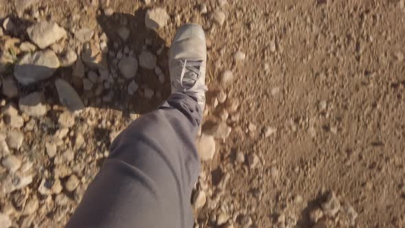 Top view on feet with hiking boots walking on desert ground