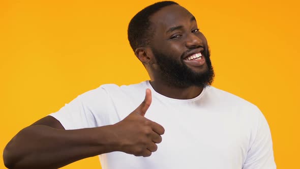 Cheerful African-American Man Showing Thumbs Up Isolated on Yellow Background