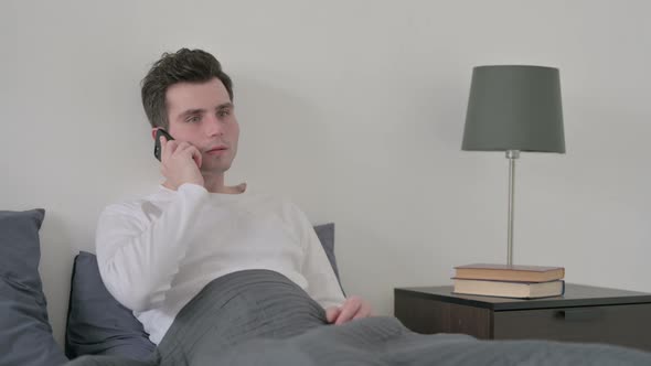 Man Talking on Call on Smartphone in Bed