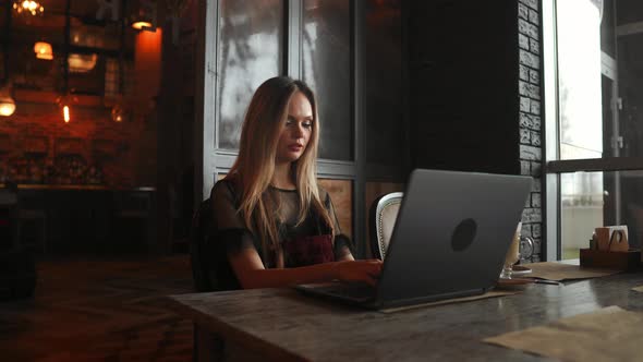 Happy Young Woman Drinking Coffee and Using Tablet Computer in Cafe