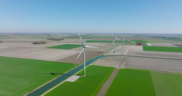 Wind turbines spinning and generating clean energy in Holland, with classic water canal crossing fla