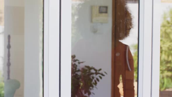 Senior man and woman touching each other through glass door