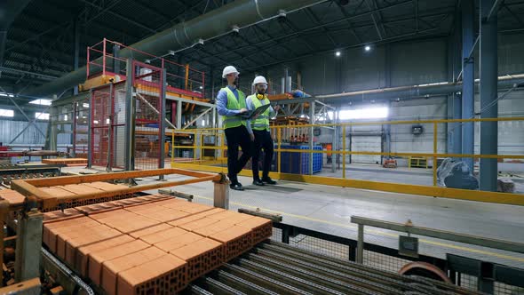 Male Engineers Walk at a Modern Industrial Plant, Checking Pallets with Bricks