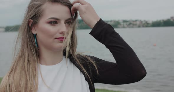 Young Smiling Girl Corrects Blowing Hair When Looking Aside on Seaside