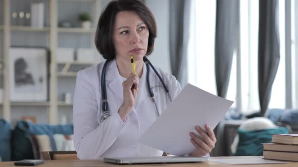 Pensive Old Lady Doctor Reading Medical Report for Treatment