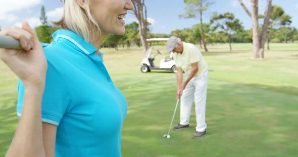 Golfer carrying golf club over shoulder while standing on the golf course