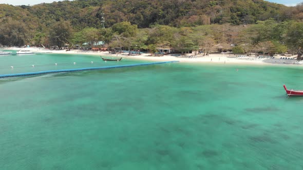 Idyllic bay with floating dock platform and rural fishing boats moored on the emerald water, Koh Hey