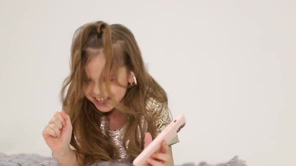 Little Girl Listens to Music with Wireless Headphones