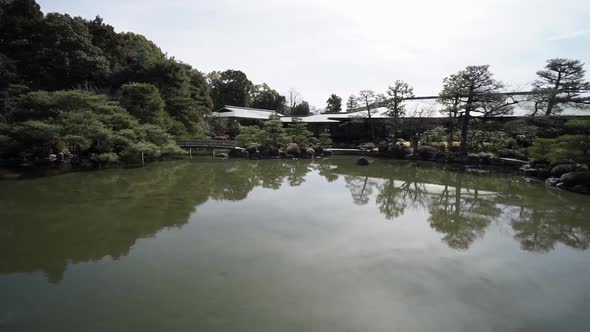 Pan left to right of a very quiet and still Japanese  pond with reflection of  a zen garden in the m