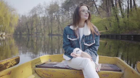 Portrait of a Young Woman in Sunglasses and a Denim Jacket Floating on a Boat