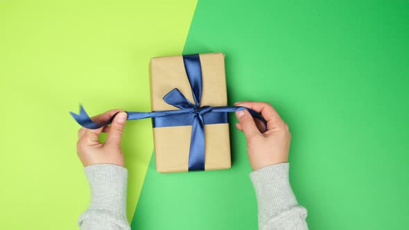 female hand puts on green surface wrapped gifts with blue tied ribbons