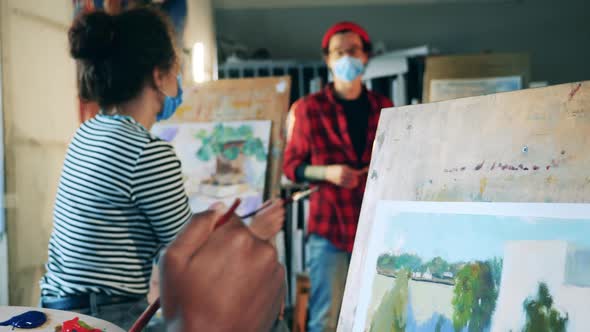 Students are Painting During Art Class with a Teacher in a Face Mask