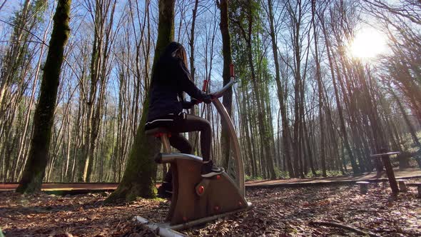 Woman Pedaling and Doing the Exercises in the Forest