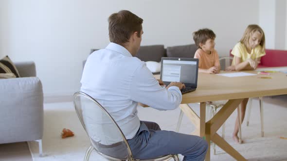 Rear View of Man Writing Email Message on Laptop Computer