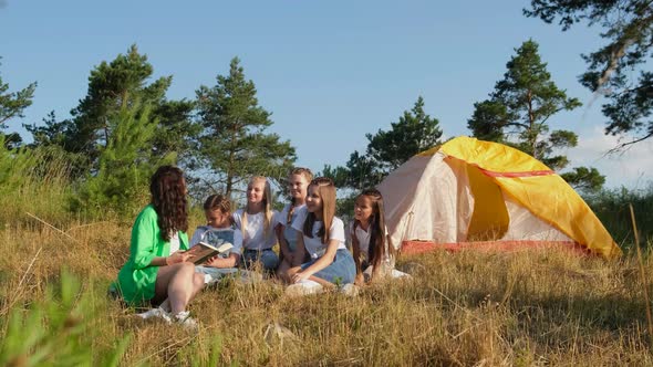 Young Teacher with Students in Camp Outdoors on Nature