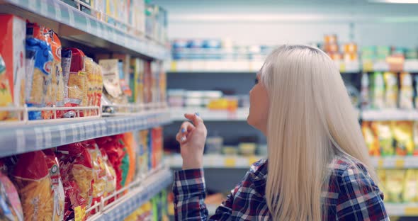 Woman Reads the Label on the Package at the Supermarket