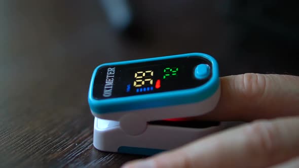 Pulse Oximeter in a Male Patient's Fingertip on Dark Wooden Table Background Medical Equipment